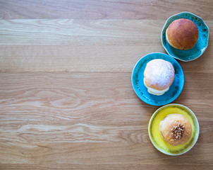 Top view of doughnuts in ceramic wares on wood background.