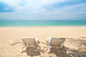 Two white Lounge Chairs on beautiful sandy Beach Background.