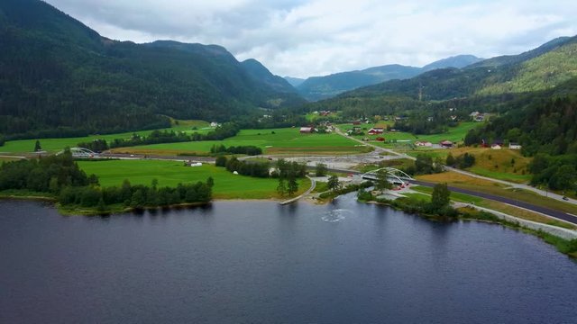 Aerial drone flight over lake Hesjadalsvatnet in a beautiful valley. A calm life in a Norwegian village in middle of mountains. Taken at summer day in municipality of Hjartdal in Telemark in Norway