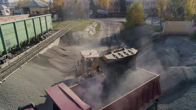 front loader loads gravel into dump truck body at construction logistics hub green wagons crushed stone