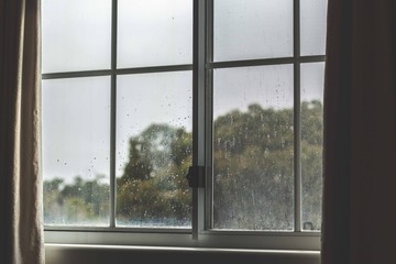 Looking outdoors through rain drop covered window on a cold winters day