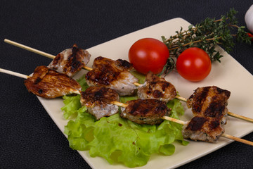 Pork kebab skewers in the plate with salad leaves and tomatoes