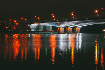 night landscape with a view of the river under the bridge in the light of lanterns. side wide view