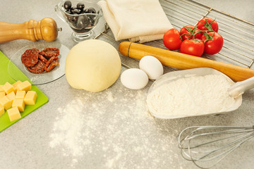 dough and ingredients for making pizza and pasta at home, on a gray countertop. lifestyle