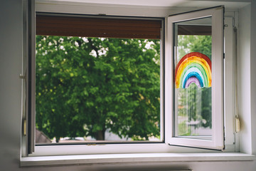 Painting rainbow on open window in room. Spring time.