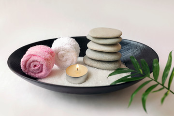 Spa still life with stones and burning candles in a Cup palm leaf on a white background. The concept of Eastern traditions, beauty and health.