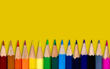 Colored pencil placed on yellow paper background with copy space for your image or text.