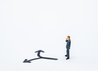 Businessman miniature people figure thinking and looking to direction left or tight arrow on white background with copy space using for business,marketing and financial concept.
