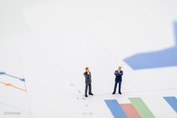 Two businessman miniature people figures meeting on graph report paper  background with copy space. Using as business, financial, money and cooperation concept.