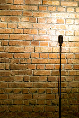 Microphone ready on stage against a brick wall