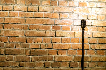 Microphone ready on stage against a brick wall