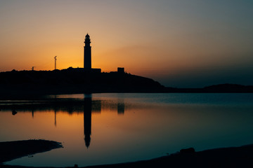 Lighthouse at sunset with reflection in the sea