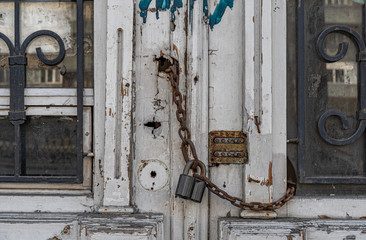 old wooden door with lock. Ornate curved gratings in door windows of abandoned retro building.