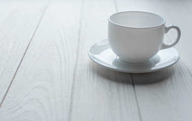 White porcelain cup on white wooden background