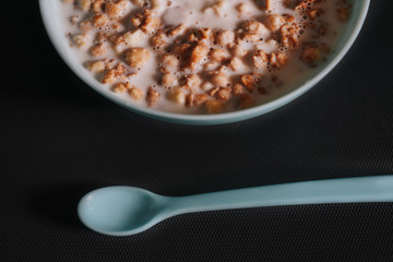 Blue bowl with musli and milk and little blue. spoon on grey background as a healthy breakfast