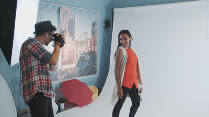 Backstage of photo shoot: multiracial young woman posing for fashion magazine photo shoot. There is white background behind the model.