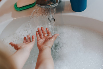 Fototapeta premium Cute little toddler girl washing her hands in a bathroom. Hygiene concept showing prevention of infection and viruses such as flu and covid-19
