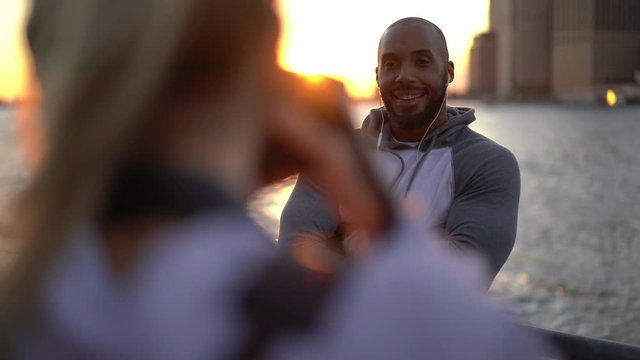 Female professional enjoying collaboration with Latin male model taking pictures of muscular body shape for advertising of sport clothing, African American bodybuilder posing for photographing
