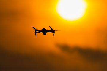 Drone flying aerial over orange sky and sun in the sunset.