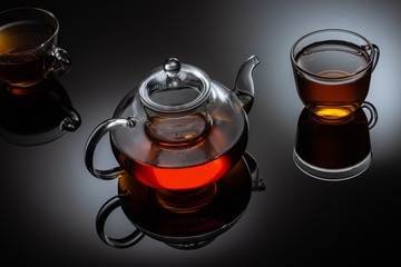 glass teapot and cup with hot tea on table, close view  