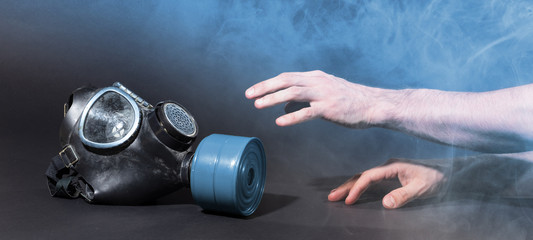 Man in room filled with smoke, trying to reach for vintage gasmask - Blue smoke