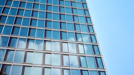 Structural glass wall reflecting blue sky. Abstract modern architecture fragment. View of a modern glass skyscraper, modern office building. Modern office facade fragment with blue glass.