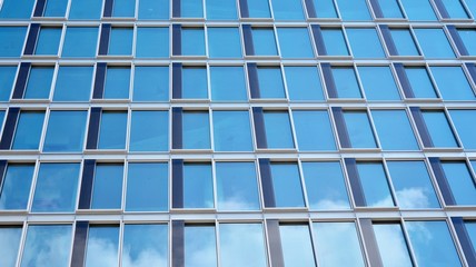 Structural glass wall reflecting blue sky. Abstract modern architecture fragment. View of a modern glass skyscraper, modern office building. Modern office facade fragment with blue glass.