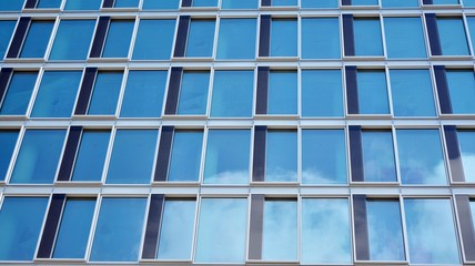 Structural glass wall reflecting blue sky. Abstract modern architecture fragment. View of a modern glass skyscraper, modern office building. Modern office facade fragment with blue glass.