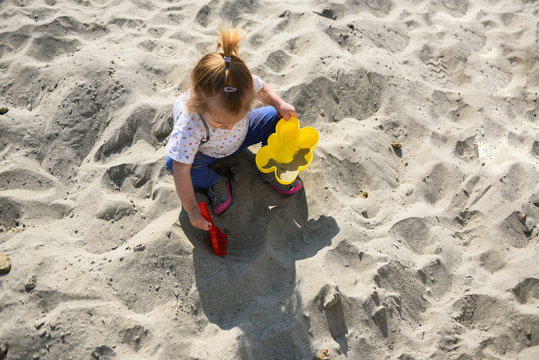 Little girl playing in the sand - close up photo of the sandy legs