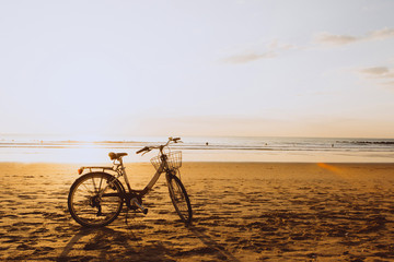 Bicycle on the ocean beach on sunset, warm orange colours