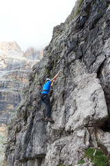 Man doing rock climbing with rope in Brenta Dolomites mountains, Italy
