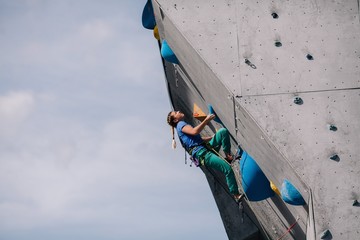 The girl climbs the climbing wall at competitions