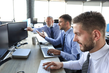 Group of young business men in formalwear working using computers while sitting in the office.