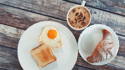 Close-up of light lunch dish with fried egg, toast and croissant