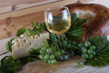 Wine, grape, cheese and bread on table