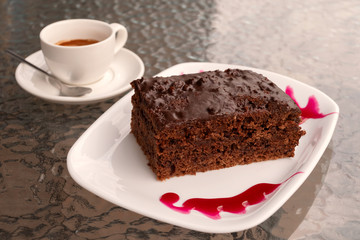Piece of chocolate brownie with cup of espresso on cafe table. American cuisine.