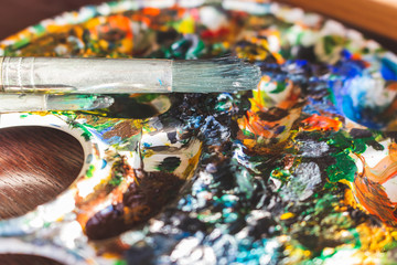Dirty palette board. Bright acrylic paints close up. Drawing concept. Art palette and brush....