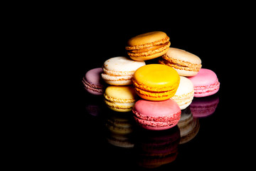 Ensemble de macarons multicolores sur fond noir avec reflets brillants