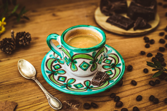 Creamy coffee in ceramic cup decorated on rustic wooden table with roasted coffee beans and chocolate on wooden table