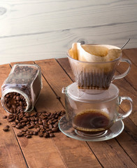 alternative brewing of coffee through a filter with coffee beans on a wooden table