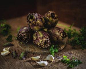 Obraz premium Fresh artichokes on top of a rustic wooden table