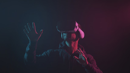 Portrait of a man in virtual reality helmet. Obscured dark face in VR goggles. Internet, darknet, gaming and cyber simulation.