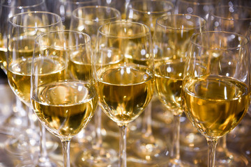 Closeup of of elegant wine glasses with white wine in a row on a table