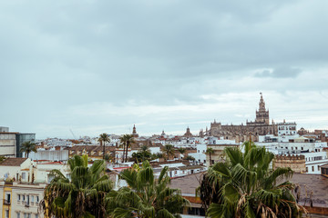 View of the Cathedral of Seville from the Torre del Oro with a cloudy sky.
