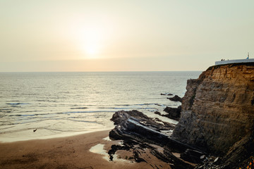 Cliff with gazebo by the sea at sunset
