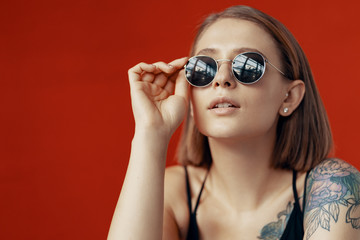 Young girl sitting on a white chair near the red wall. Natural light from the window