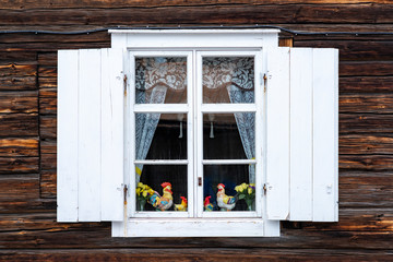 Easter Holiday window decor viewed from outside on wooden Swedish cabin. Exterior Window with white...