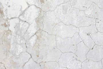 the background of the cracked white wall of the house is old covered with plaster and the paint is peeling from time. Very old house. cracks in the wall