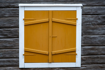Decorative Wood work window shutters on aged timber cabin. Swedish church village window shutters on wooden timber lodge.