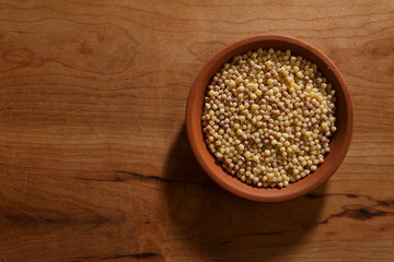 Fregola sarda dentro ciotola in ceramica, sopra tavolo di legno